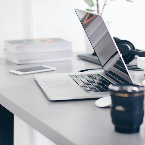 Some tech products placed on a table - Laptop and Phone and a cup of cofee